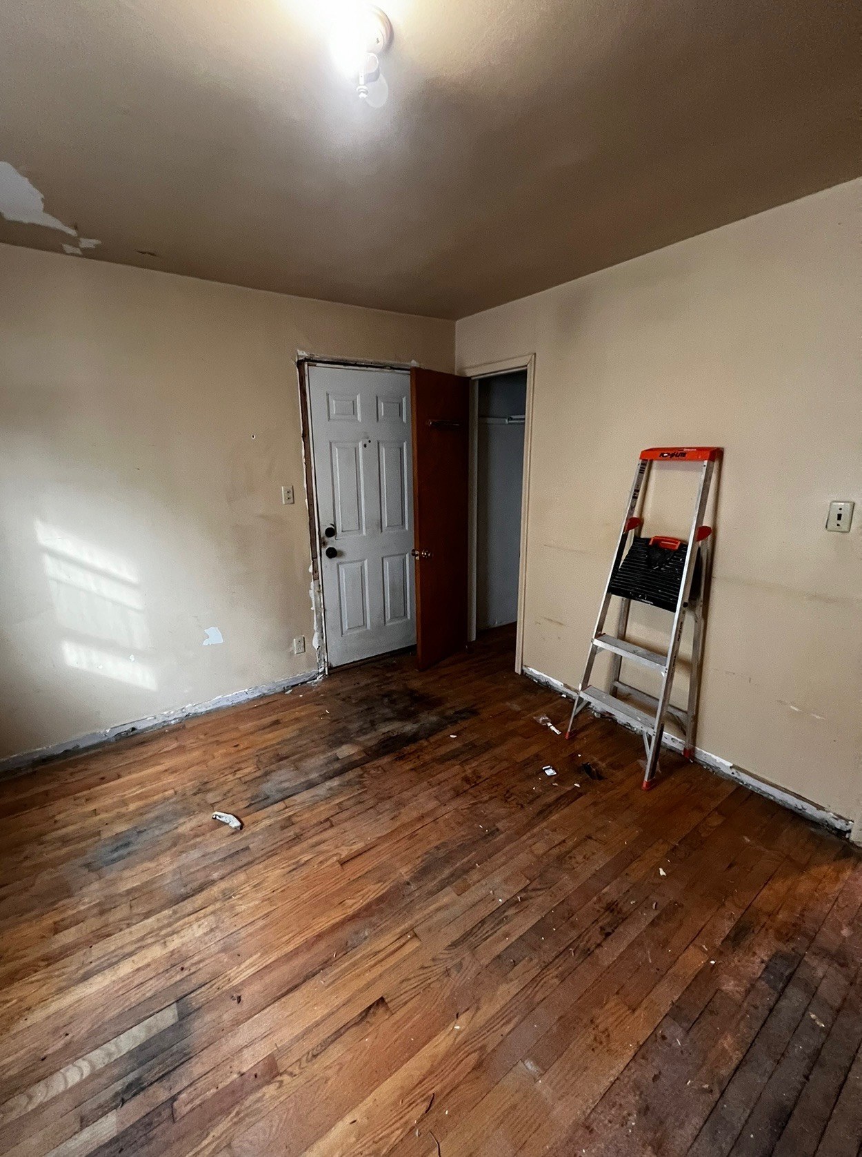 Bedroom with damaged walls and floors before remodel
